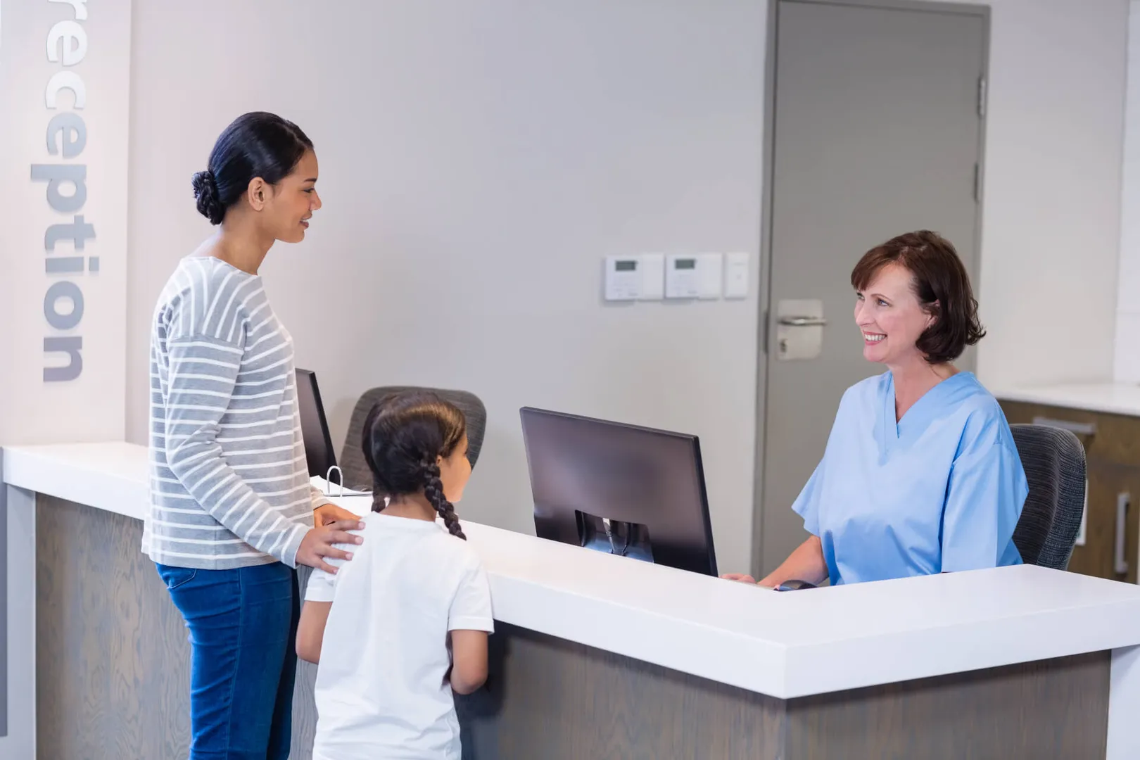 Mother and child check in at hospital reception.