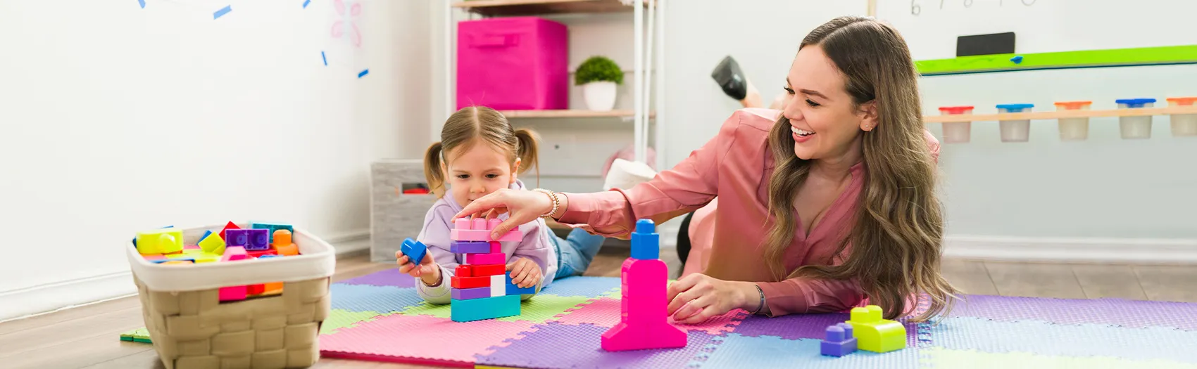 Child and adult playing with colorful building blocks.